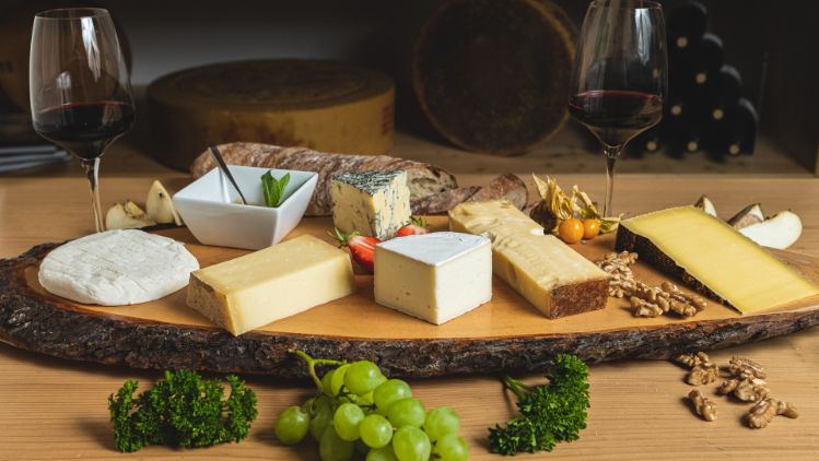 Eine Variation von Käse mit Schweizer Herkunft, passender Wein, Brot und Früchte. Diese Käseplatte ist bei Chäsbueb erhältlich.