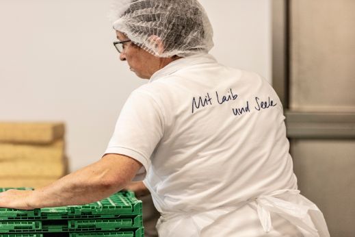 Das Bild zeigt eine Mitarbeiterin in der ChäsChuchi beim Transportieren von Käse. Baumann Käse verarbeitet und konfektioniert die Käse weiter.