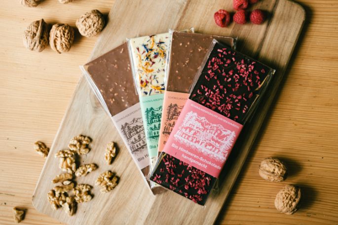 Milchschokolade aus dem Emmental mit Baumnüssen. Die Scherenschnitte auf der Verpackung von Esther Gerber sind der Emmentaler Kunst gewidmet und die handgemachten Schokoladen Tafel den lokalen Rohstoffen